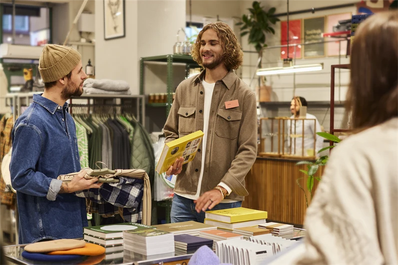 Man som jobbar i butik samtalar med kunder.