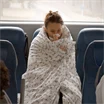 Förkyld kvinna invirad i täcke på bussen på väg till jobbet.